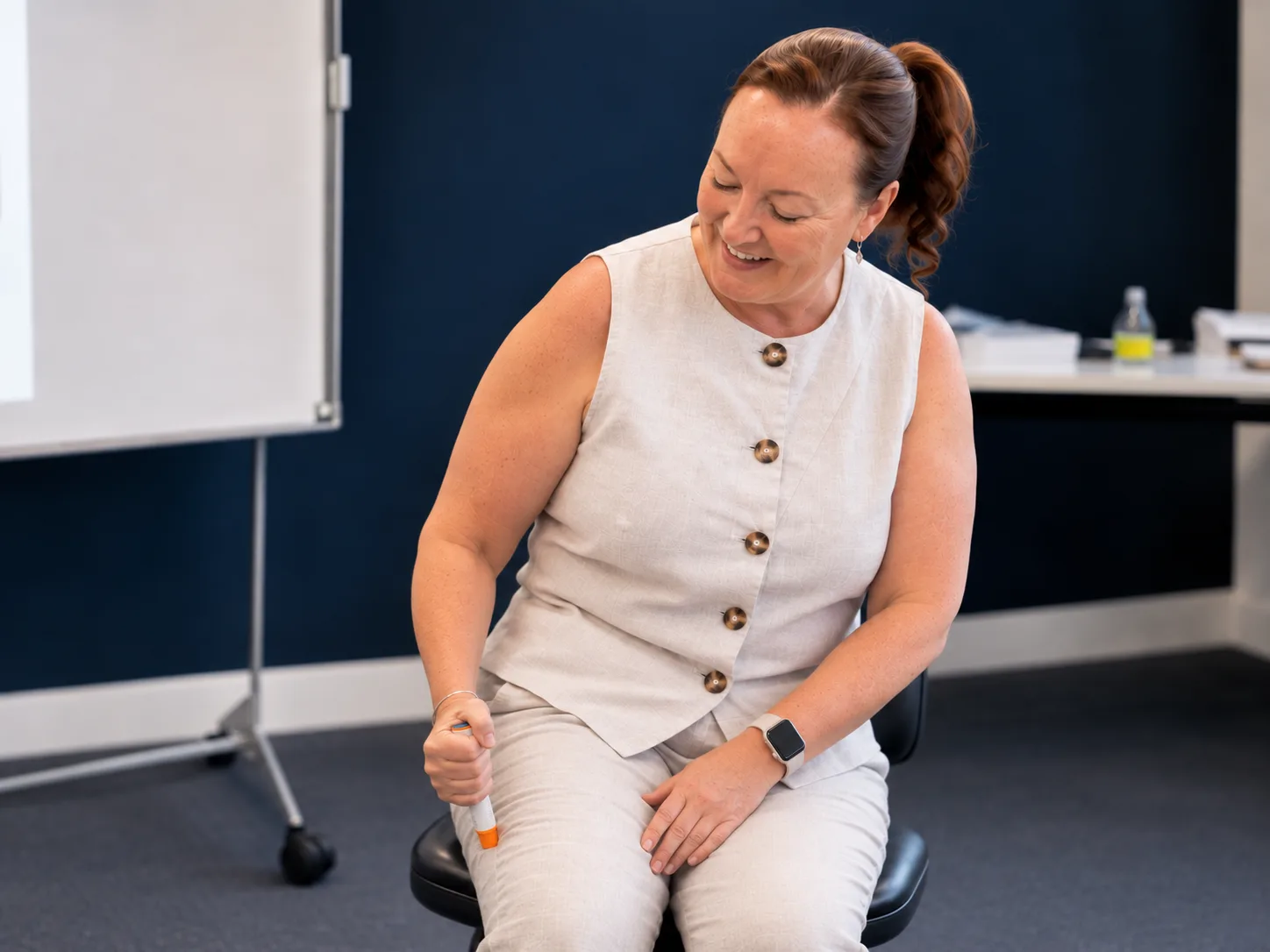 Pam demonstrating how to use a trainer adrenaline auto-injector during a training session