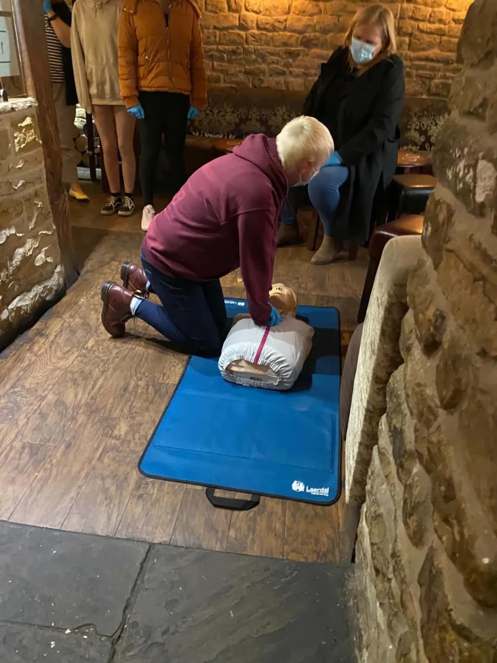 Pam leading a hands-on CPR demonstration with a group of participants