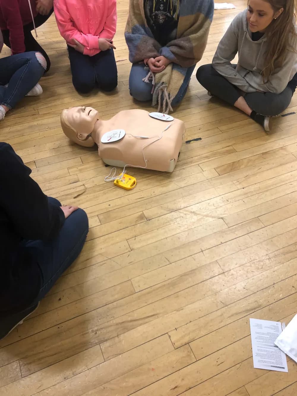 A group practising AED and CPR technique on a training mannequin