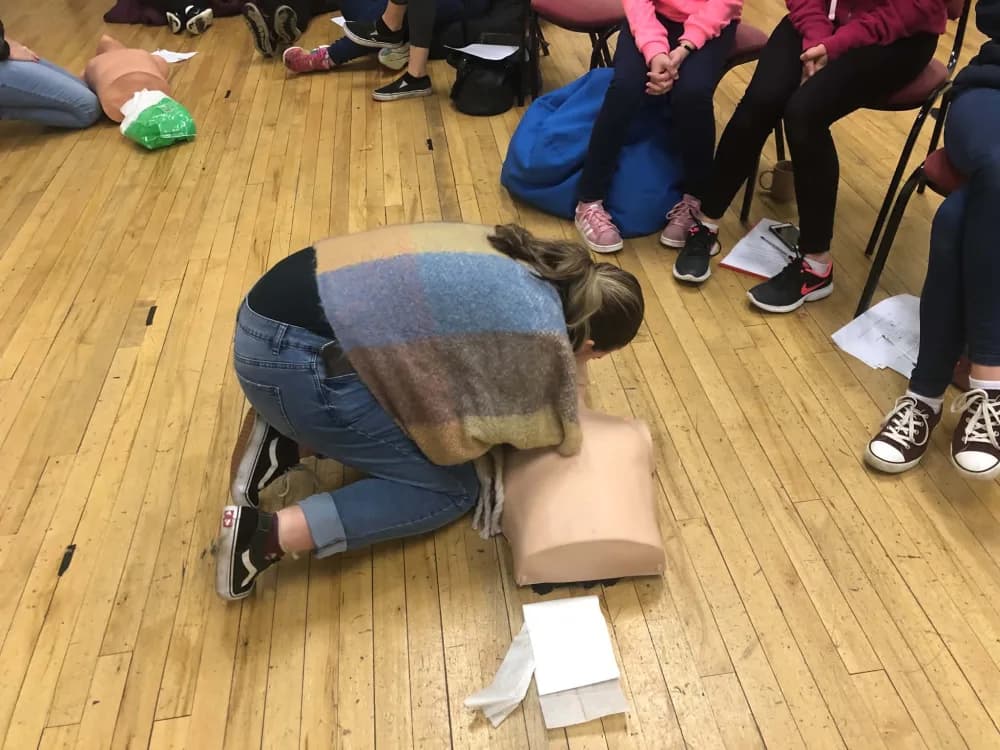 A participant practising chest compressions on a training mannequin